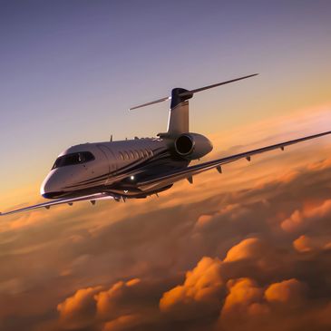 Private jet flying above clouds during sunset with vibrant sky.