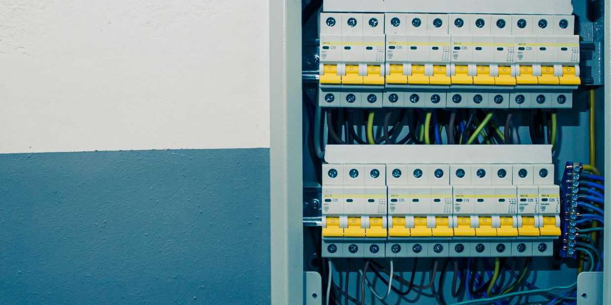 Close-up of an electrical circuit breaker panel with yellow switches and multiple wires.