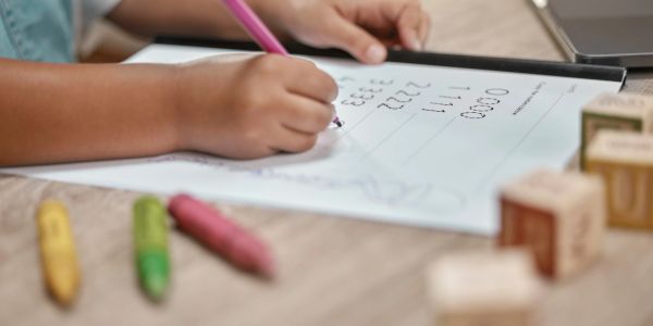 Child practicing writing numbers on paper.