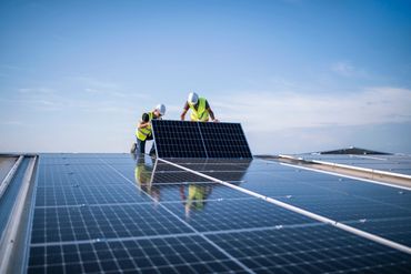 Solar installation team positioning photovoltaic panels on a commercial rooftop.
