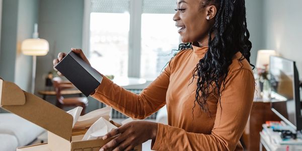 Woman happily unboxing a package in a cozy living room.