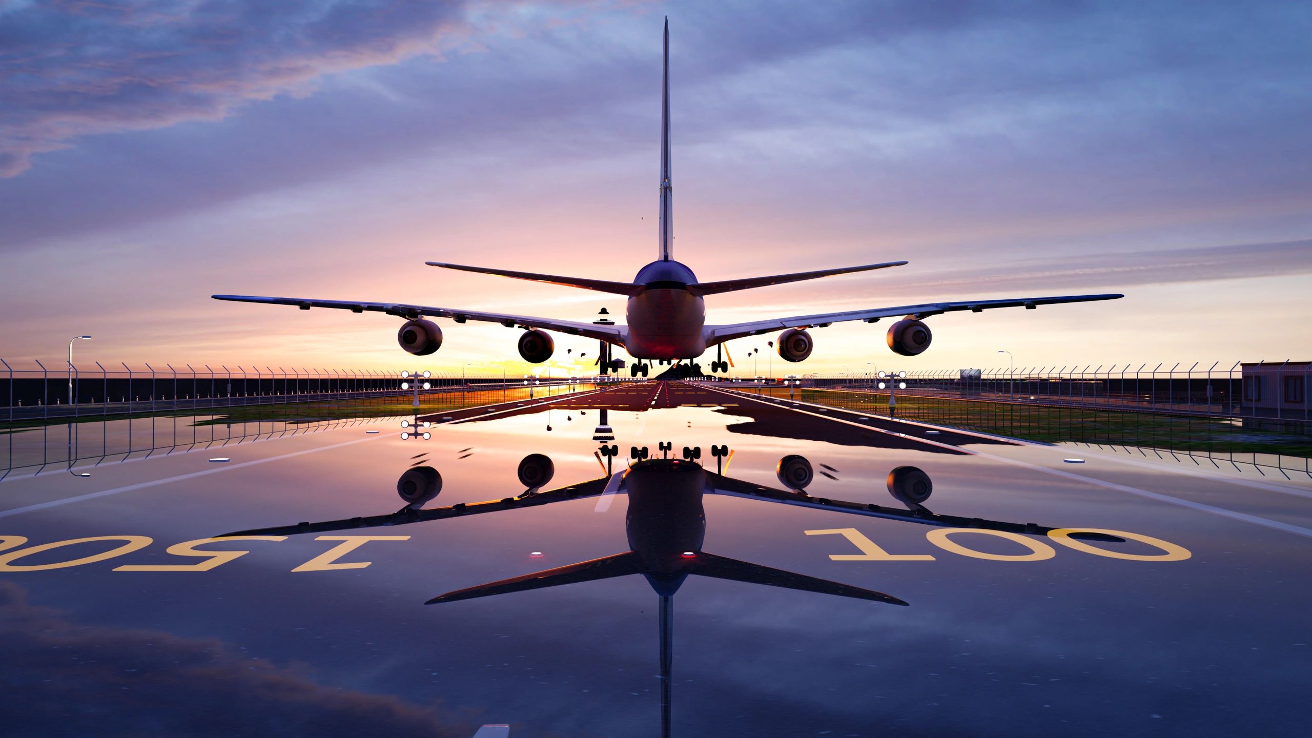 A large airplane landing on a wet runway during sunset.