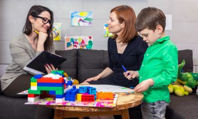 Woman and child interacting with a therapist or teacher.