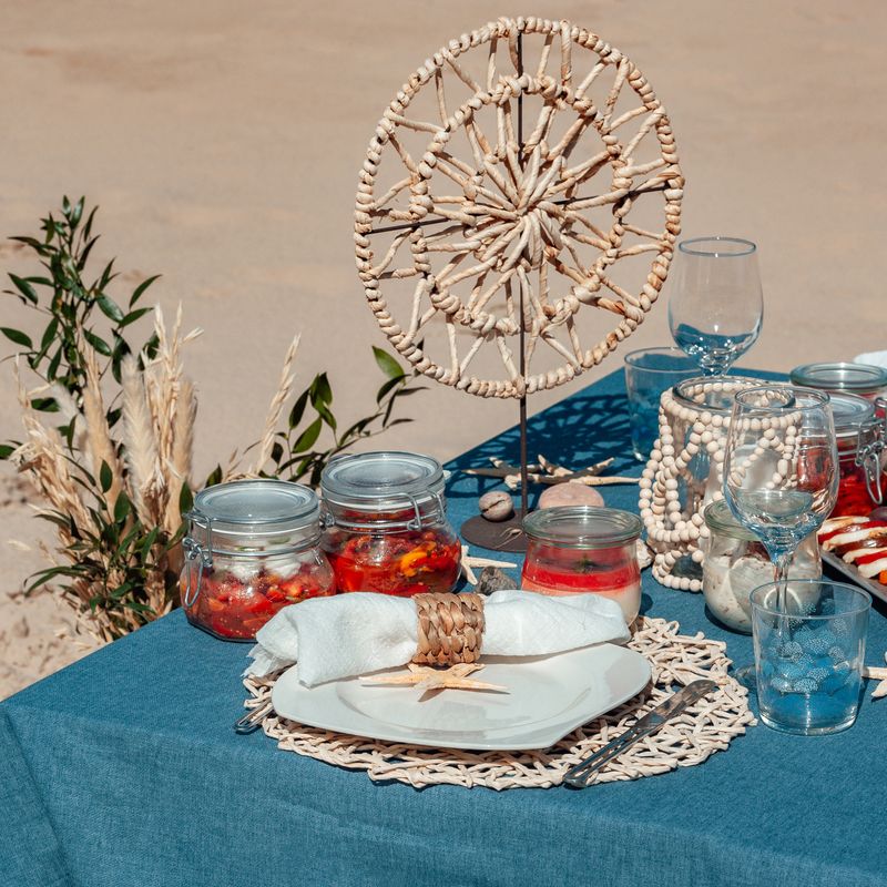 Beautiful table setting with plate, white napkin, braided decorative ring and starfish. Picnic in the style of boho.