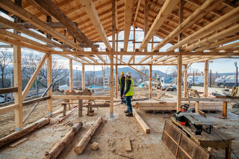 Construction workers in building site of wooden house.