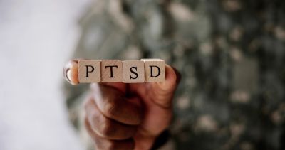 Hand holding blocks spelling PTSD.