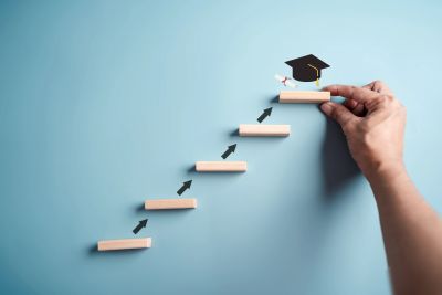 Hand placing the final step with a graduation cap on top.