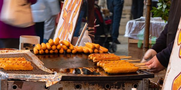 Corndogs being fried on a griddle. 