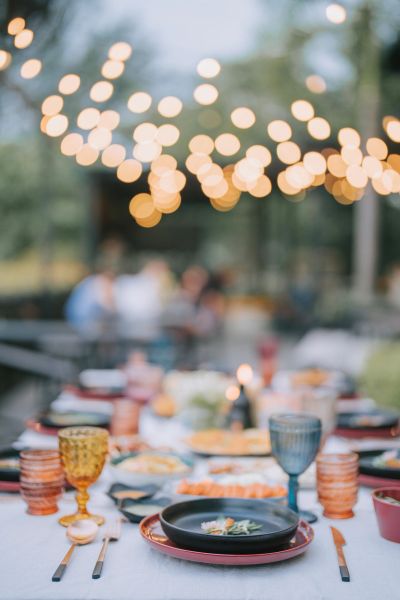 Outdoor dinner table with blurred lights and people.