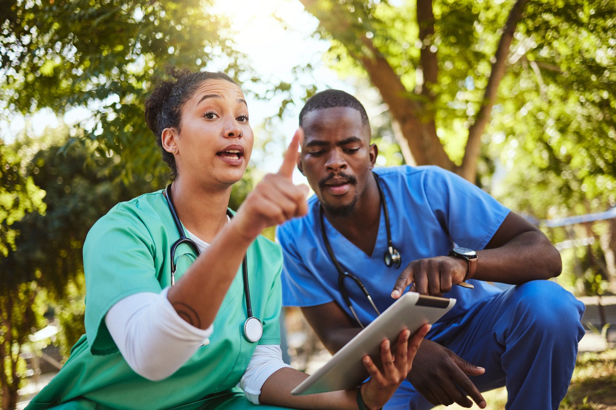 Two healthcare workers discussing something outdoors.