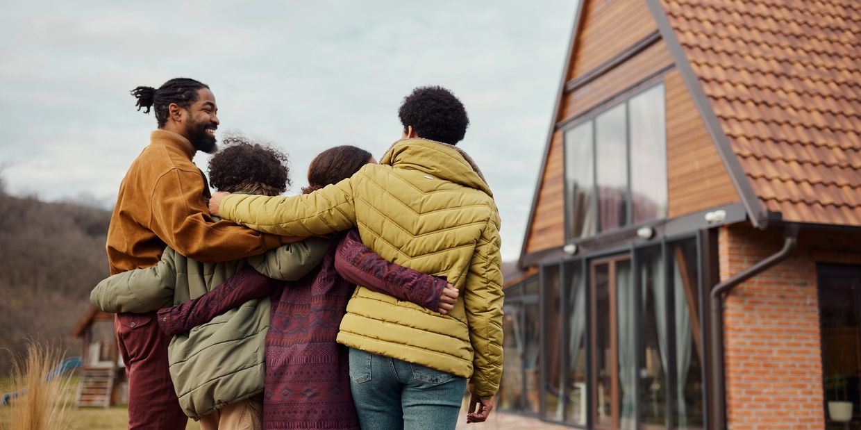 Family standing together outside a home, symbolizing protection, stability, and peace of mind.