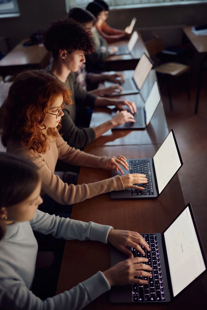 High angle view of high school students studying over laptops on a class at school. Focus is on redhead girl.