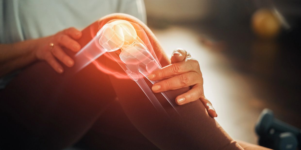 Person holding knee with highlighted joint pain illustration.