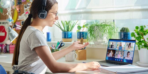 Woman wearing headphones participating in a video conference call at home.