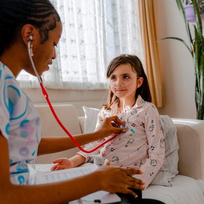 Doctor examines girl's heart with stethoscope.