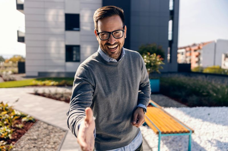 A real estate agent giving handshake in front of the property.
