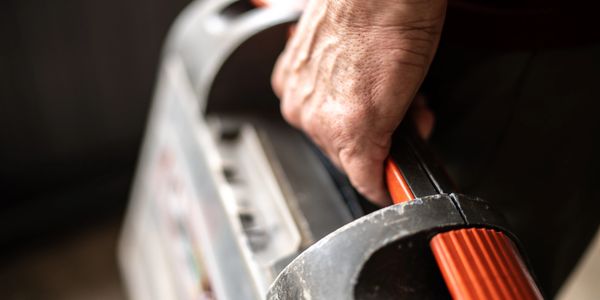 Close-up of a hand gripping a handle on a vintage portable radio.