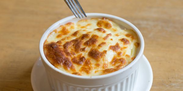 Golden-brown baked dish in a white ramekin on a wooden table.