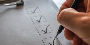 Hand marking checkboxes on a clipboard checklist.