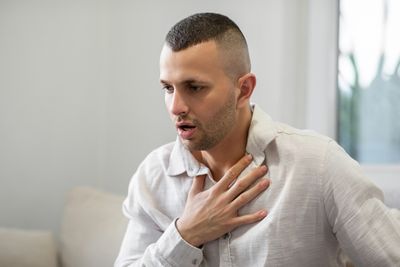Man clutching his chest, appearing to have chest pain.