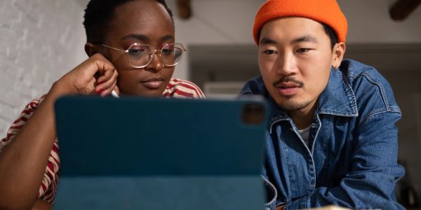 Two people looking at a tablet screen together.