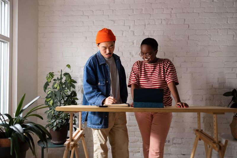 Beautiful mixed race couple working on their art project at their bright studio with plants