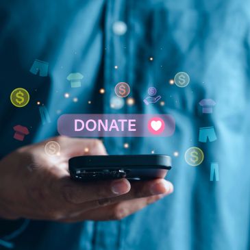 Hand holding a phone with a digital donate button.