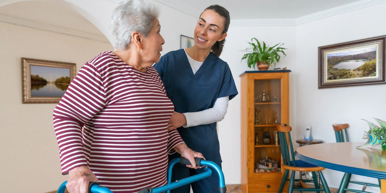 Caregiver assisting elderly woman with walker at home.