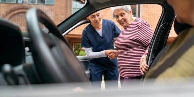 Nurse helping elderly woman into car.