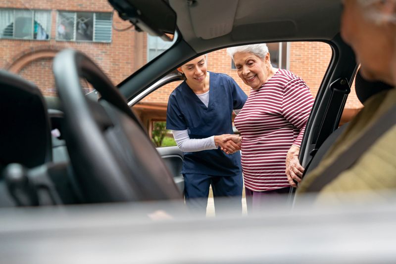 Home caregiver helping a happy senior woman get inside a car â assisted living concepts