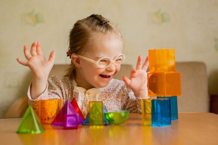 Joyful child playing with colourful translucent shapes during a speech and language therapy session.