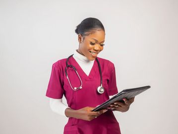 Nurse smiling while looking at a tablet.