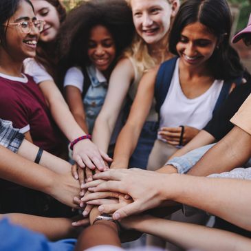 A diverse group of friends stacking their hands together in unity.