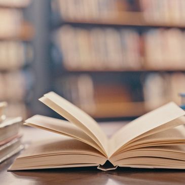 An open book on a wooden table in a library.
