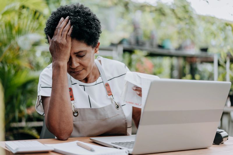 Store manager worried about debts with hand on head
