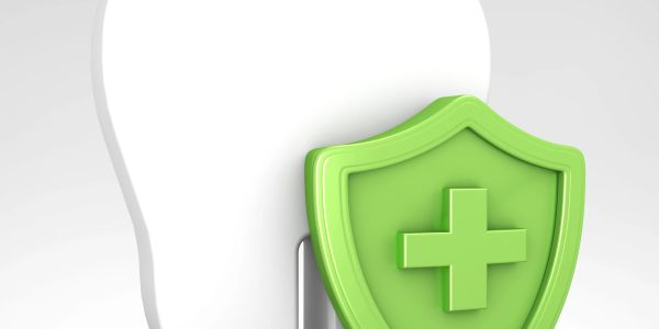White tooth with a green shield featuring a medical cross symbol.