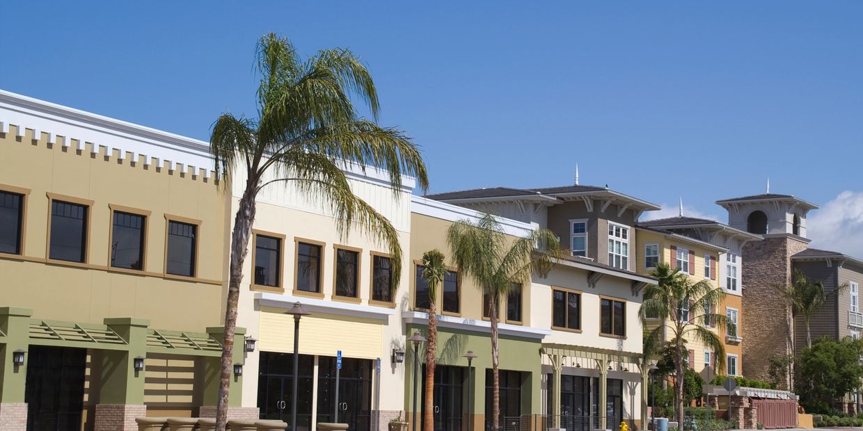 Modern commercial buildings with palm trees under a clear blue sky.