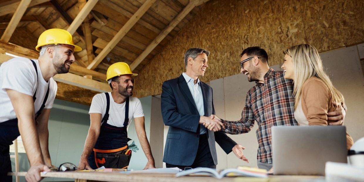 Construction workers and clients shaking hands and smiling.