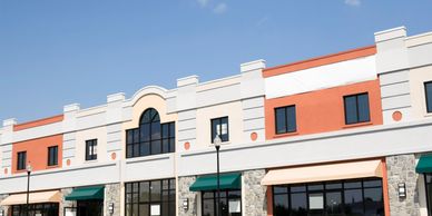 Modern commercial building with large windows and awnings under a clear blue sky.