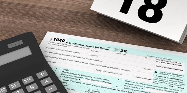 Calculator, pencil, and tax form on desk with April 18 calendar date.