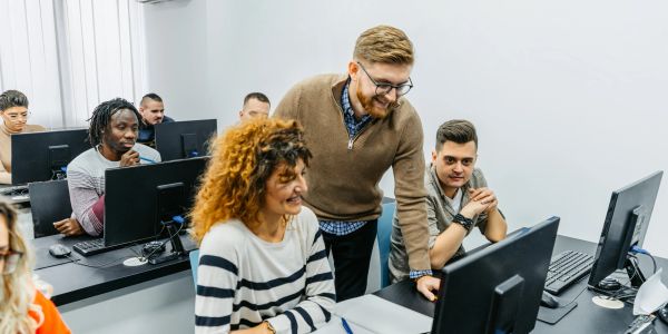 Teacher helping students in a computer lab.