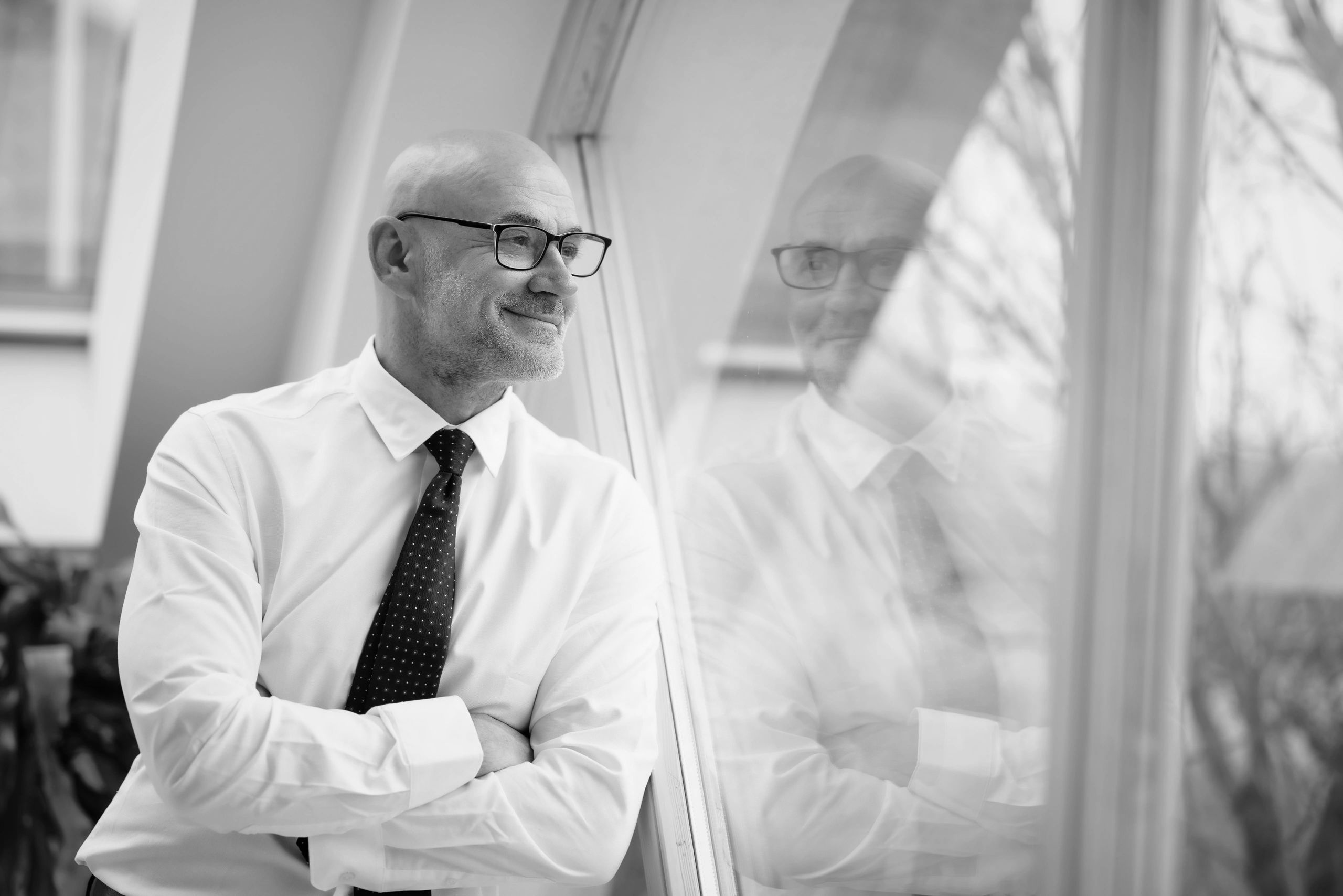 A charming gray house on a grassy hill by the ocean under a clear blue sky.