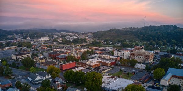 A small town at sunset with colorful skies and a mix of buildings and greenery.