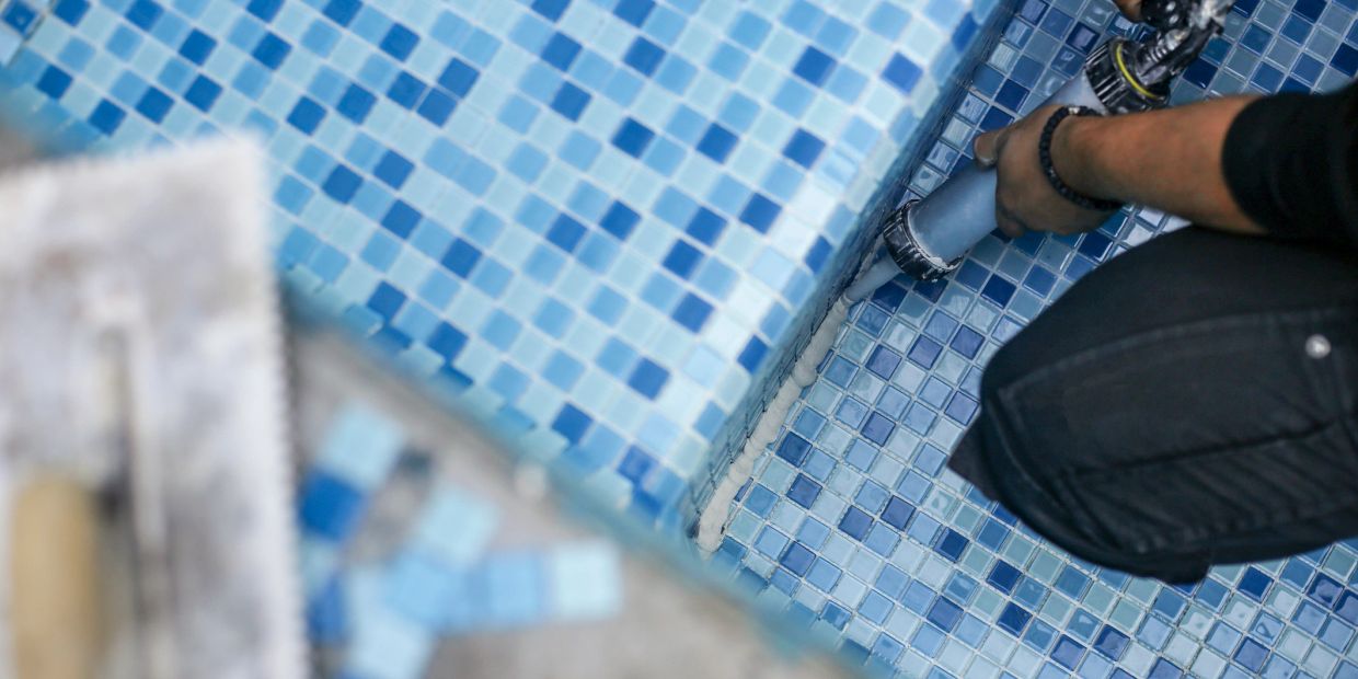 Applying sealant on blue tiled surface.