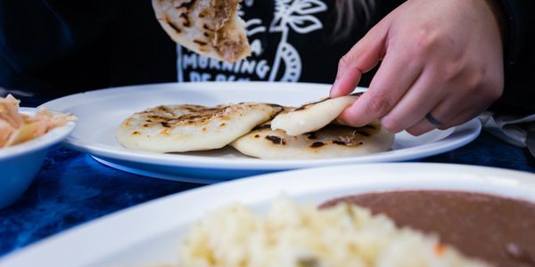 Hand tearing a piece of flatbread with food dishes on a table.