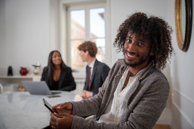 A group of young business people during a meeting, close up on young African entrepreneur smiling