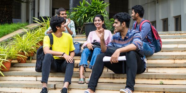 Group of students chatting happily on steps outside a building.