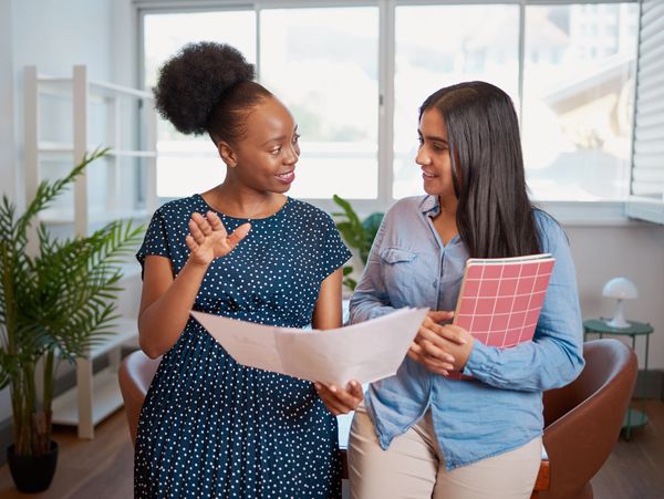 Two women discussing papers in an office.