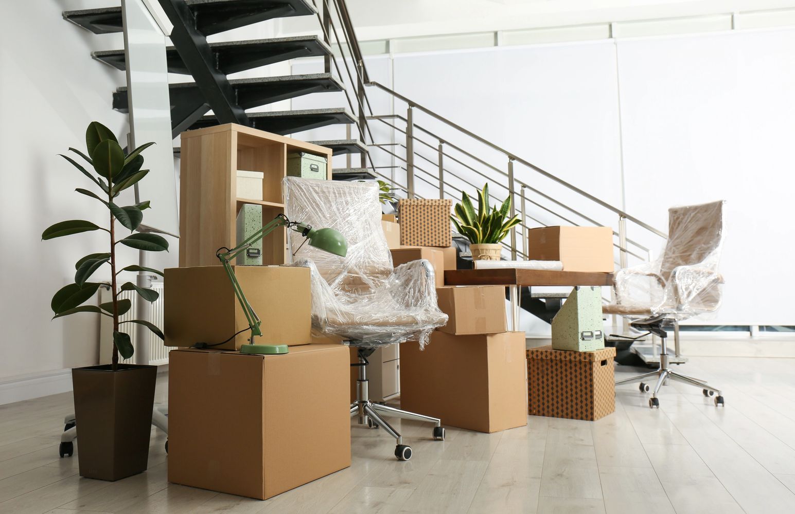 Office space with packed boxes and furniture wrapped in plastic.