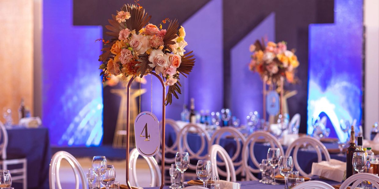 Elegant wedding tables with floral centerpieces and blue lighting.